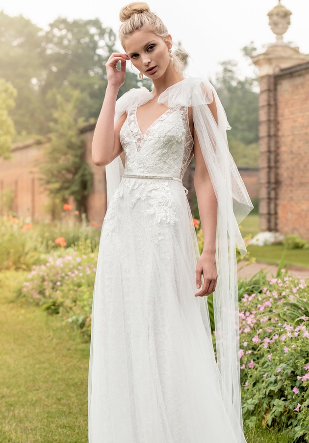 Bride poses in walled garden in Kelsey Rose dress