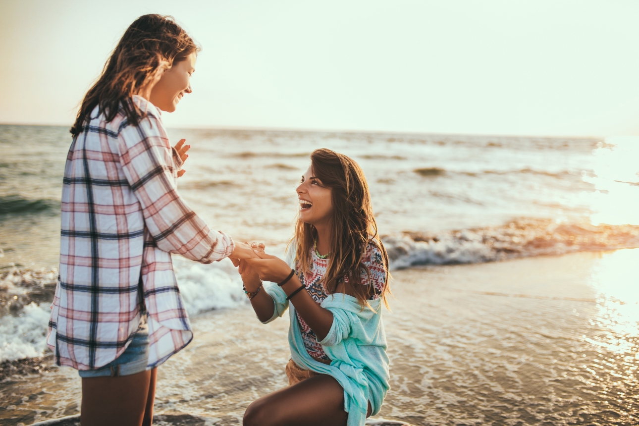 couple on a beach one on bended knee proposing 
