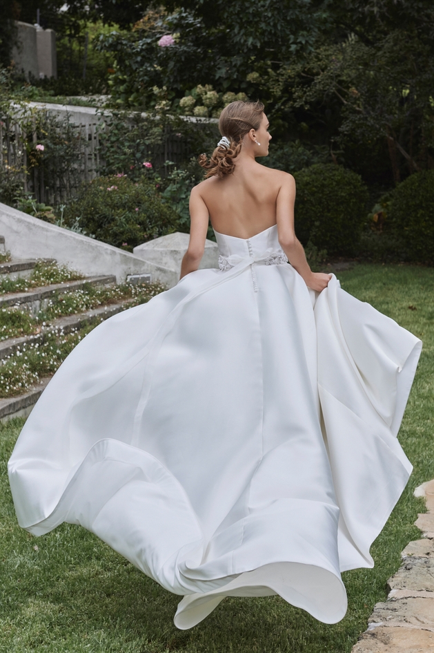 model wearing off white gown with bow on the back 