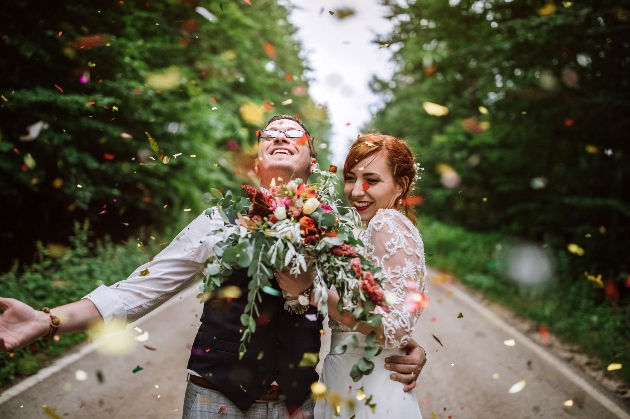 couple in wedding outfits under confetti