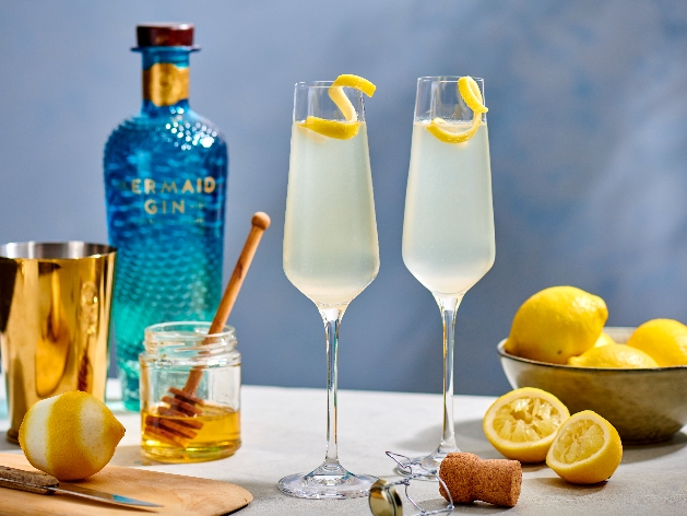 Bottle of Mermaid gin with two champagne flutes with lemon peel