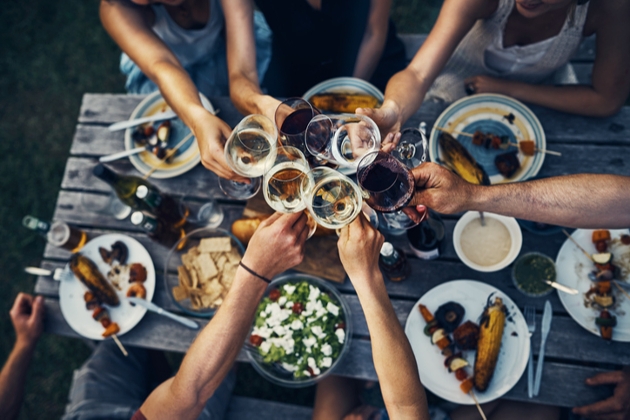 people sat at a dinner table raising their glasses for a toast