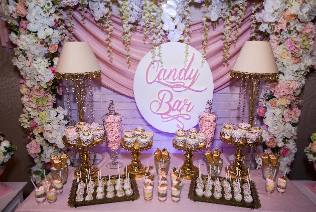 candy bar with pink and white treat on gold serving platters flower backdrop