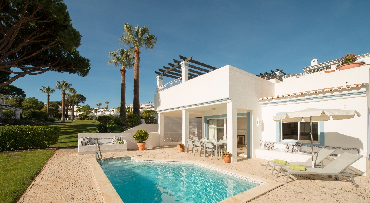 white villa with pool and sun lounges on the terrace