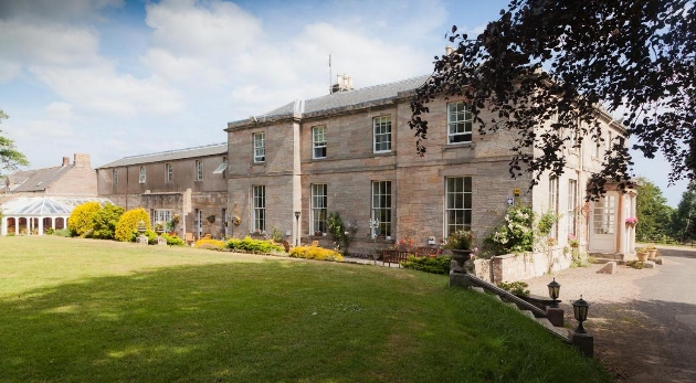 grey stone manor house with gardens