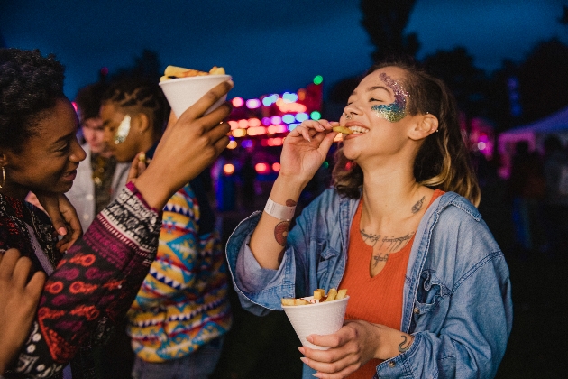festival goers at night eating chips with glitter makeup on