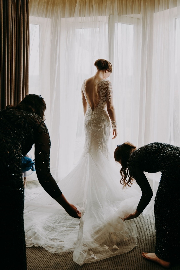 Bridesmaids adjust bride's dress