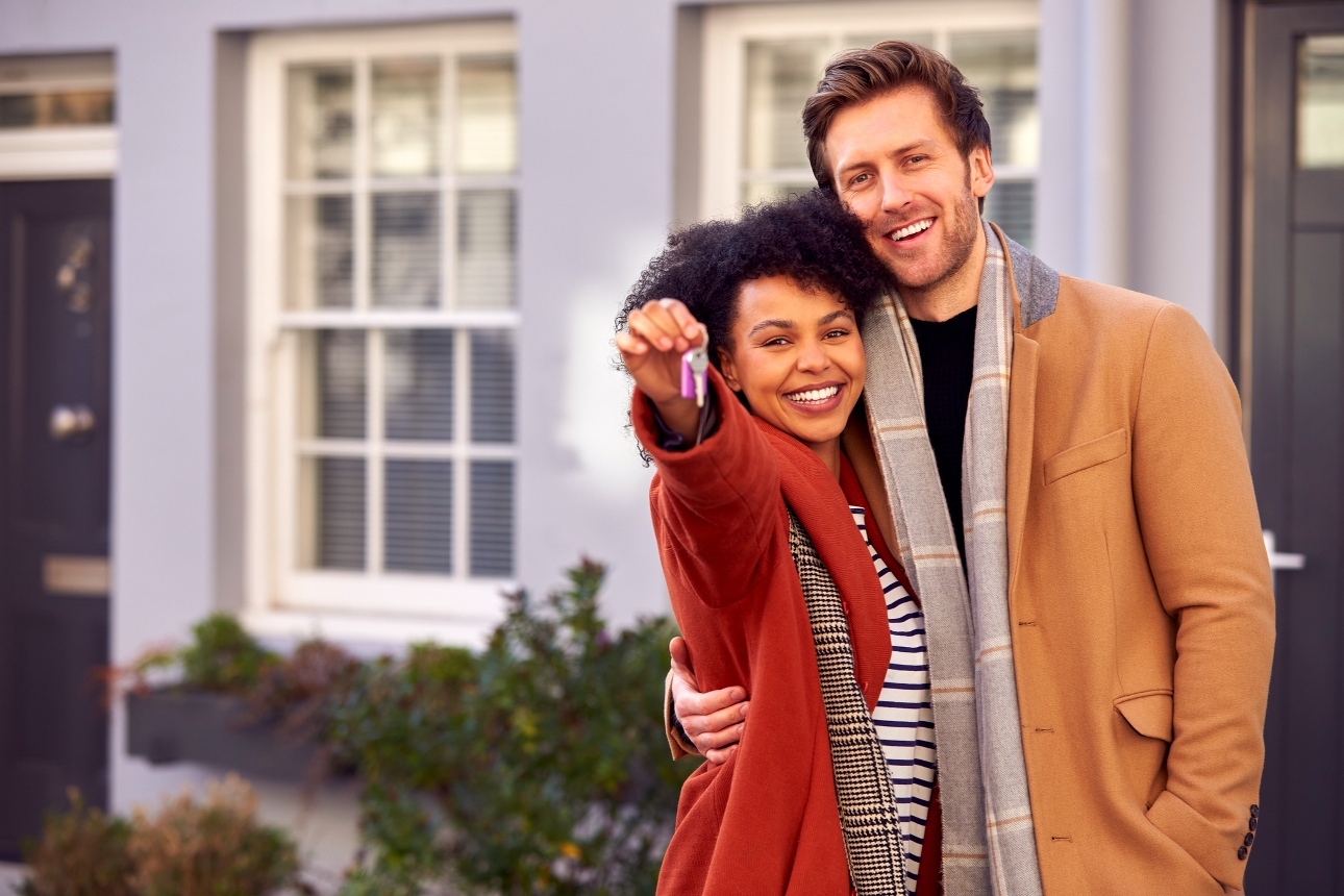 couple standing outside new home with keys