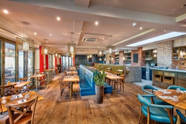 interior restaurant, wood flooring, wood tables with leather chairs, open bar and brickwork