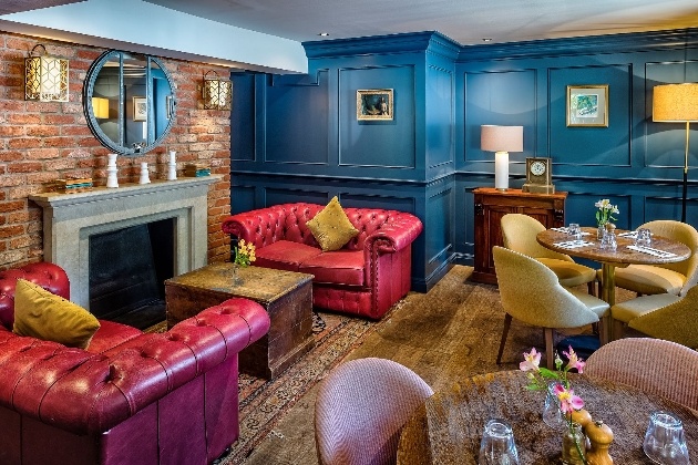 hotel lounge area blue walls, brick wall with fireplace red leather chairs