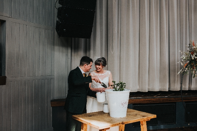 couple on their wedding day planting a plant 