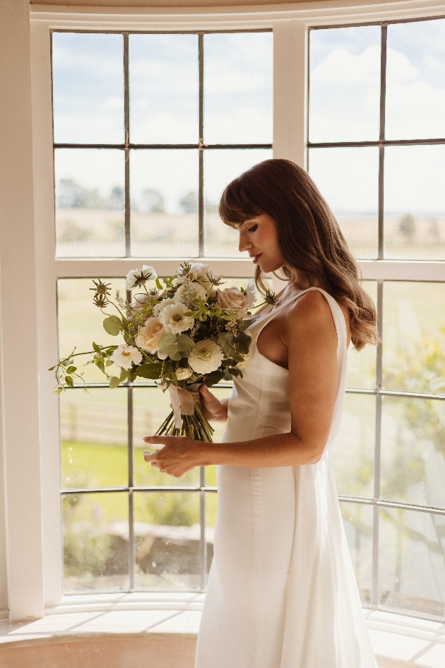 bride with bouquet in front of window