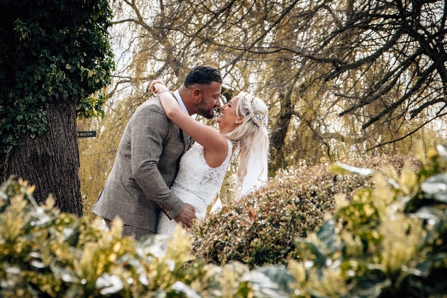groom leaning to kiss bride in garden 