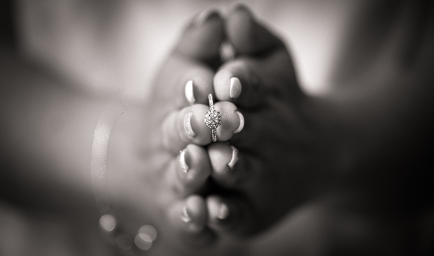 black and white image of hands holding an engagement ring