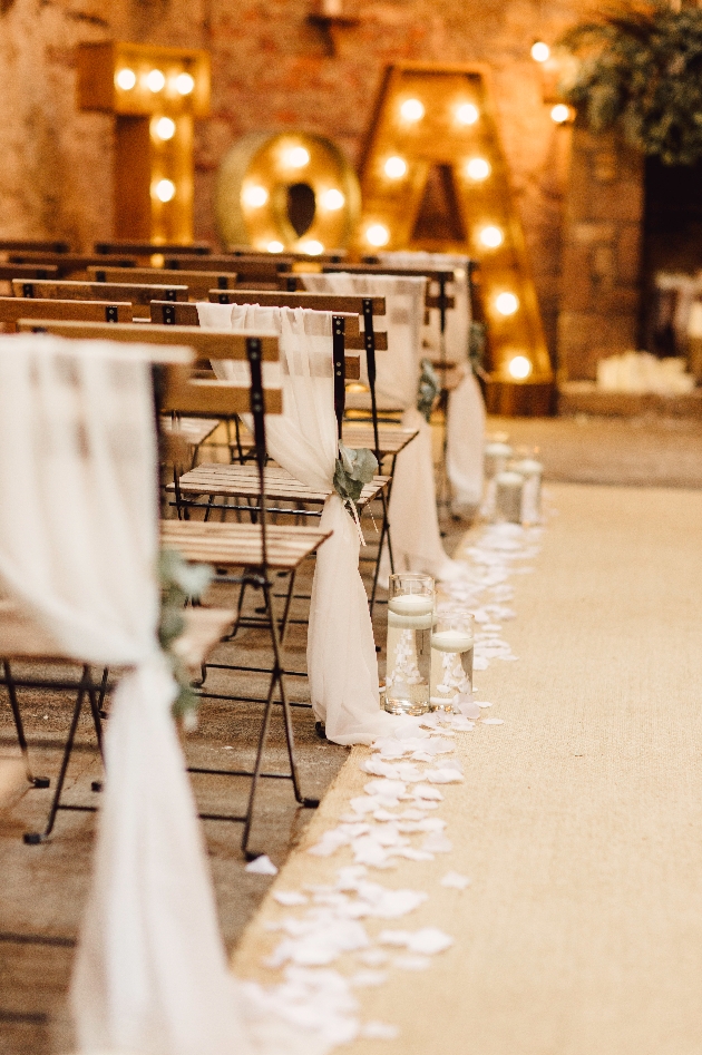 chairs with material on down aisle with love sign in background