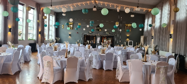 A green room with round tables and lanterns hanging from the ceiling