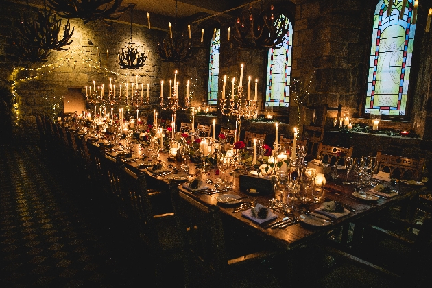 A dark room with a long table decorated with candles