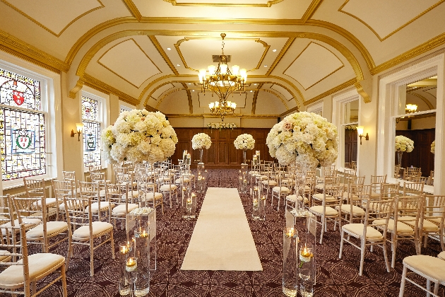 A gold room with chairs and a white aisle runner