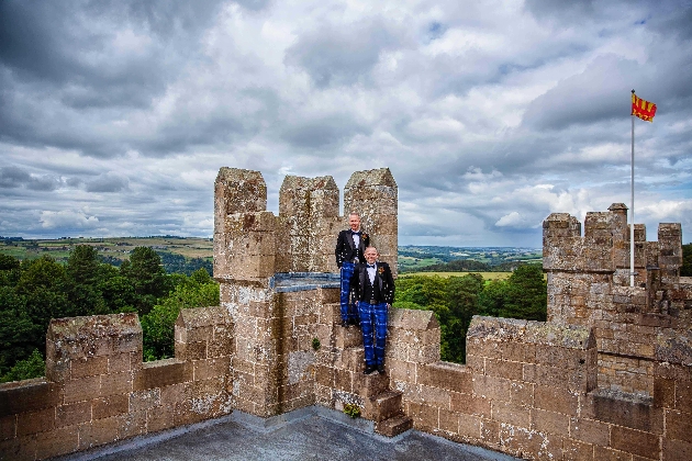 Two men wearing kilts standing on the roof of a castle