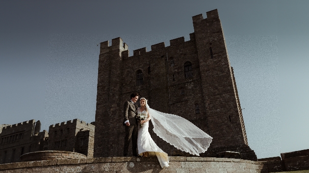 A bride and groom standing in front of a castle